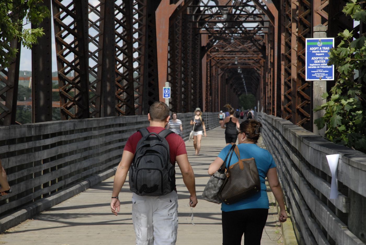 People walking through the steel truss of the Bill Thorpe Walking Bridge